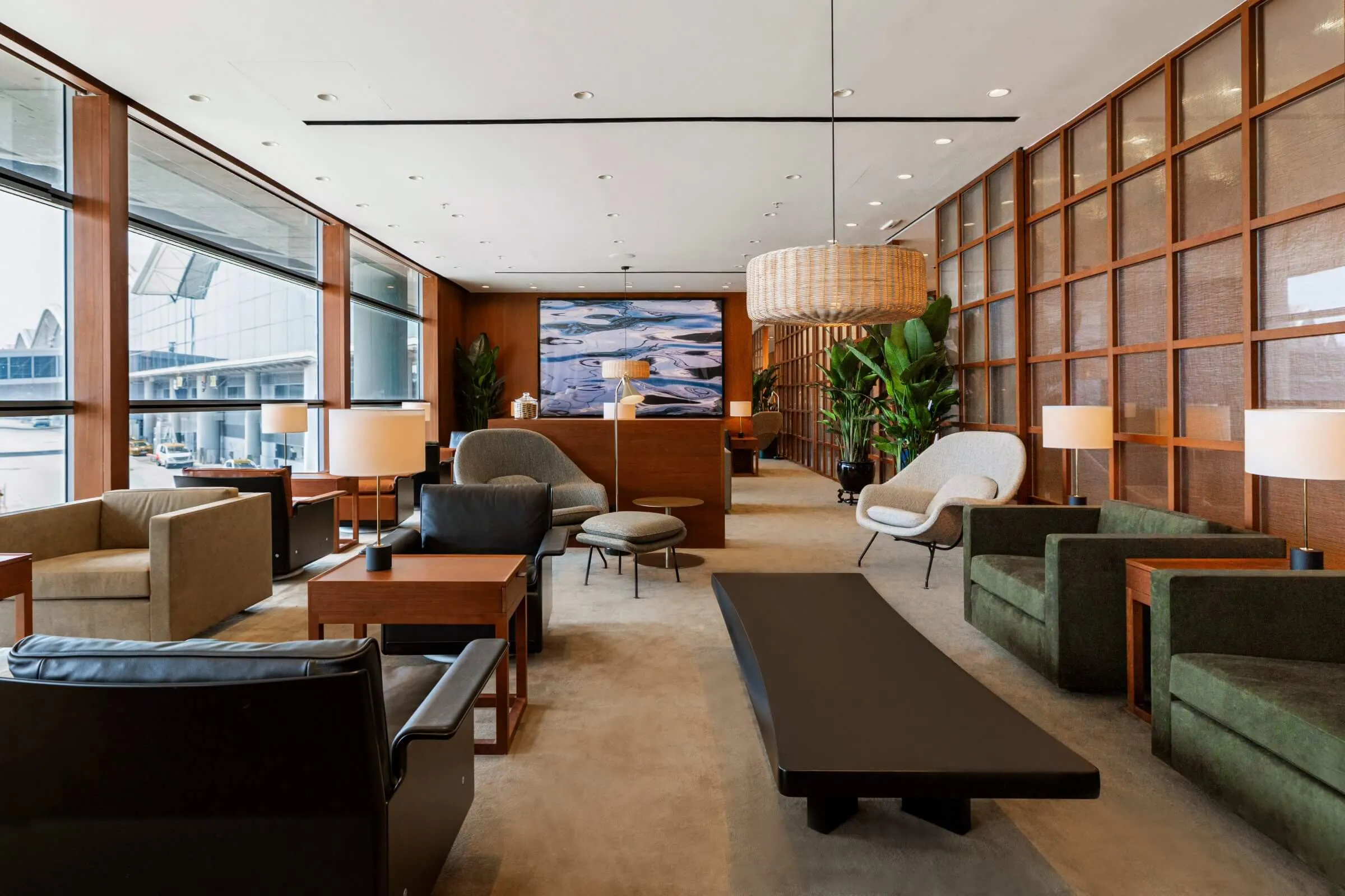 Cathay Pacific lounge with green seating, timber screens, woven pendant lights and airport views