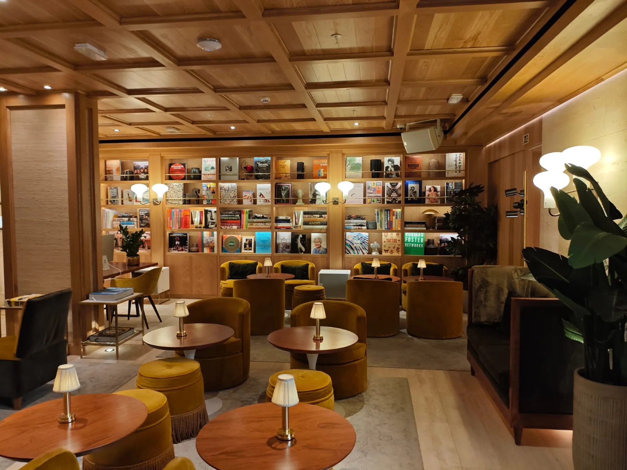 Brown’s Avenue Hotel lounge with wooden bookshelves, wall lamps and ochre upholstered chairs