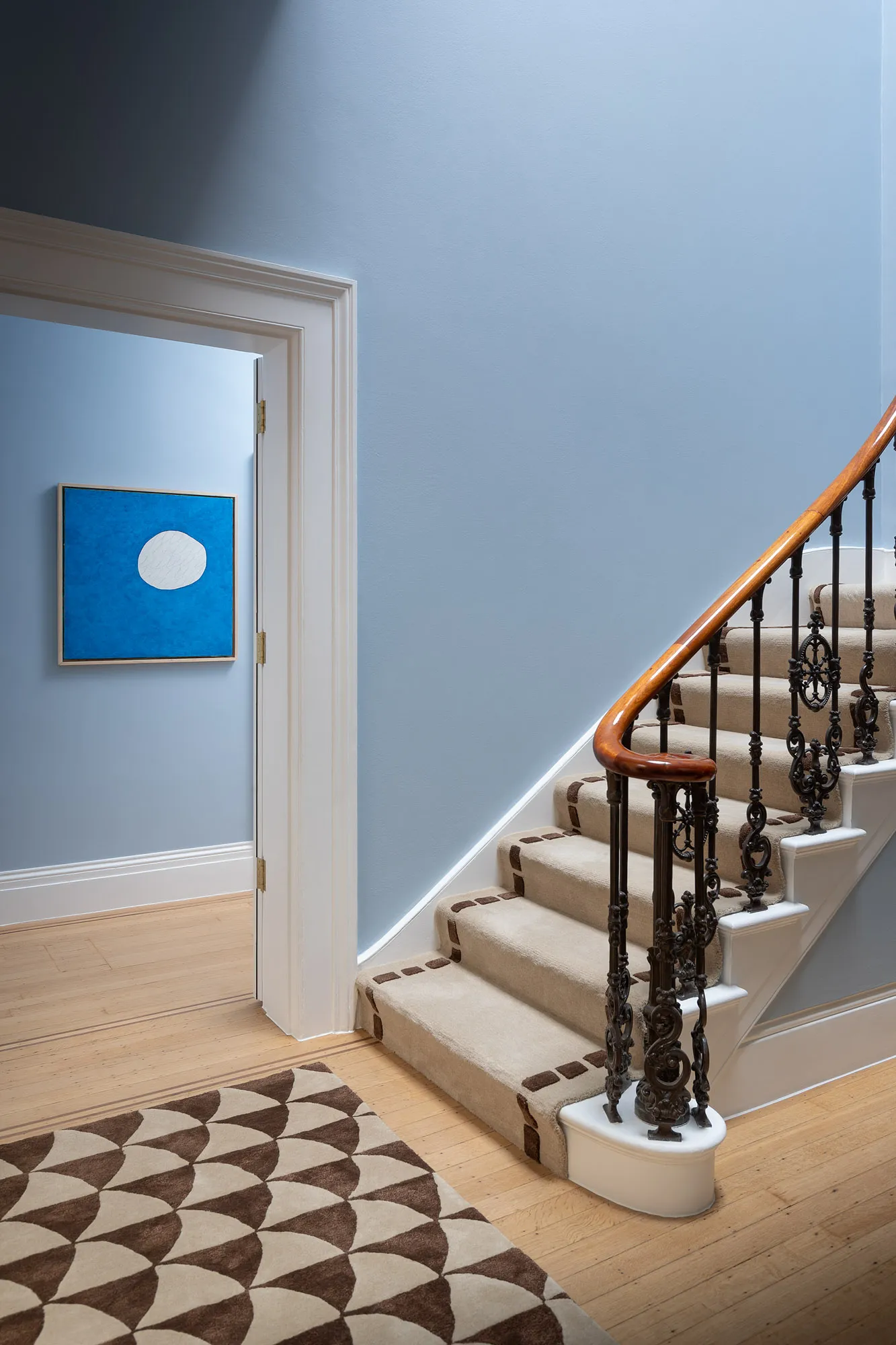 Staircase and blue walls in the ambassador’s residence, with a framed artwork by the landing
