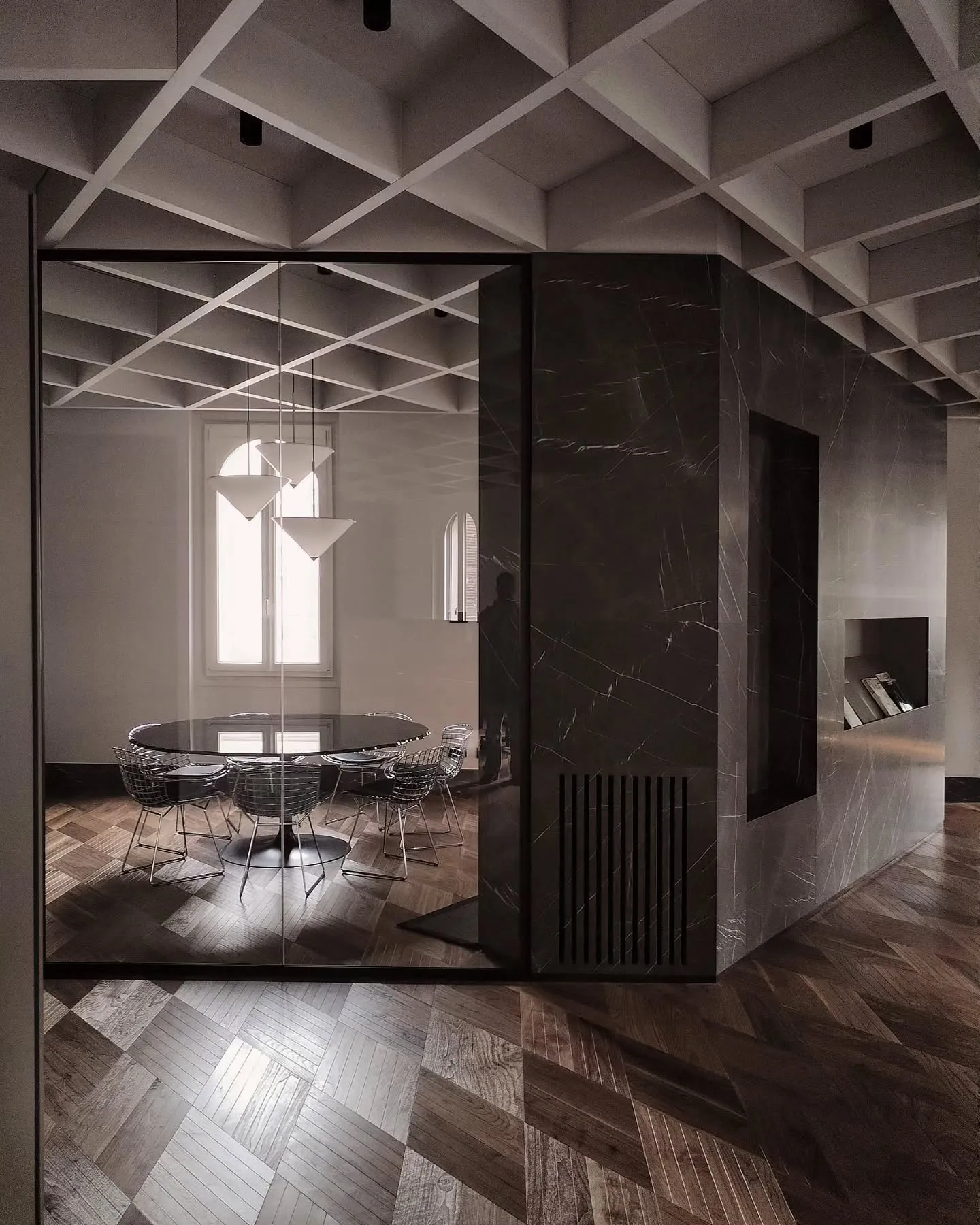 Marble-clad central volume and glass meeting rooms beneath a geometric ceiling