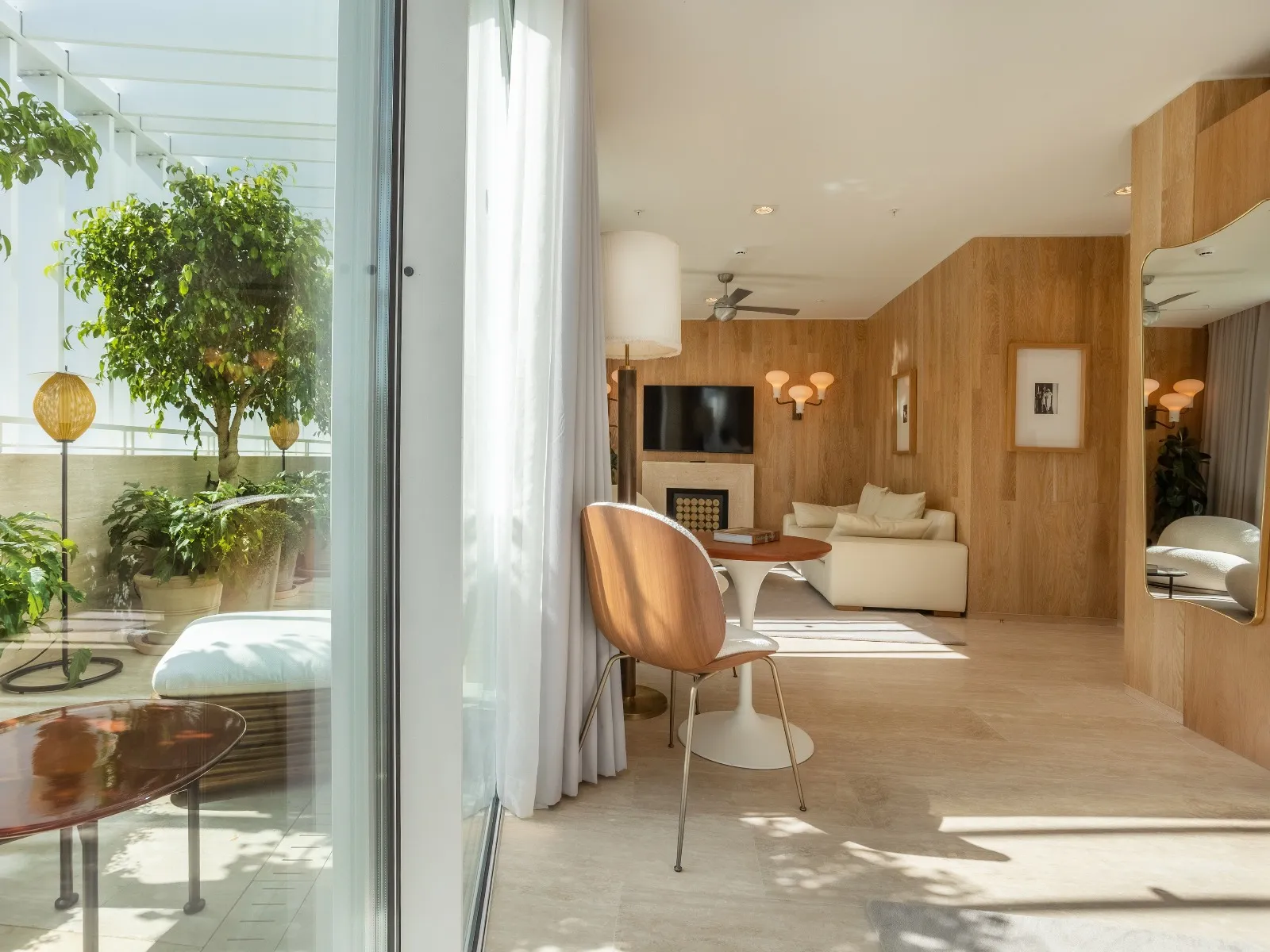 Bright Brown’s Avenue Hotel guest room with pale seating, a wall lamp and a planted terrace