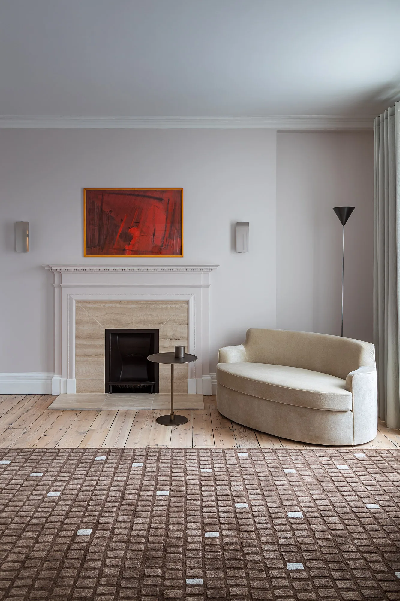 Pale sofa, fireplace and red artwork in a sitting room at the ambassador’s residence